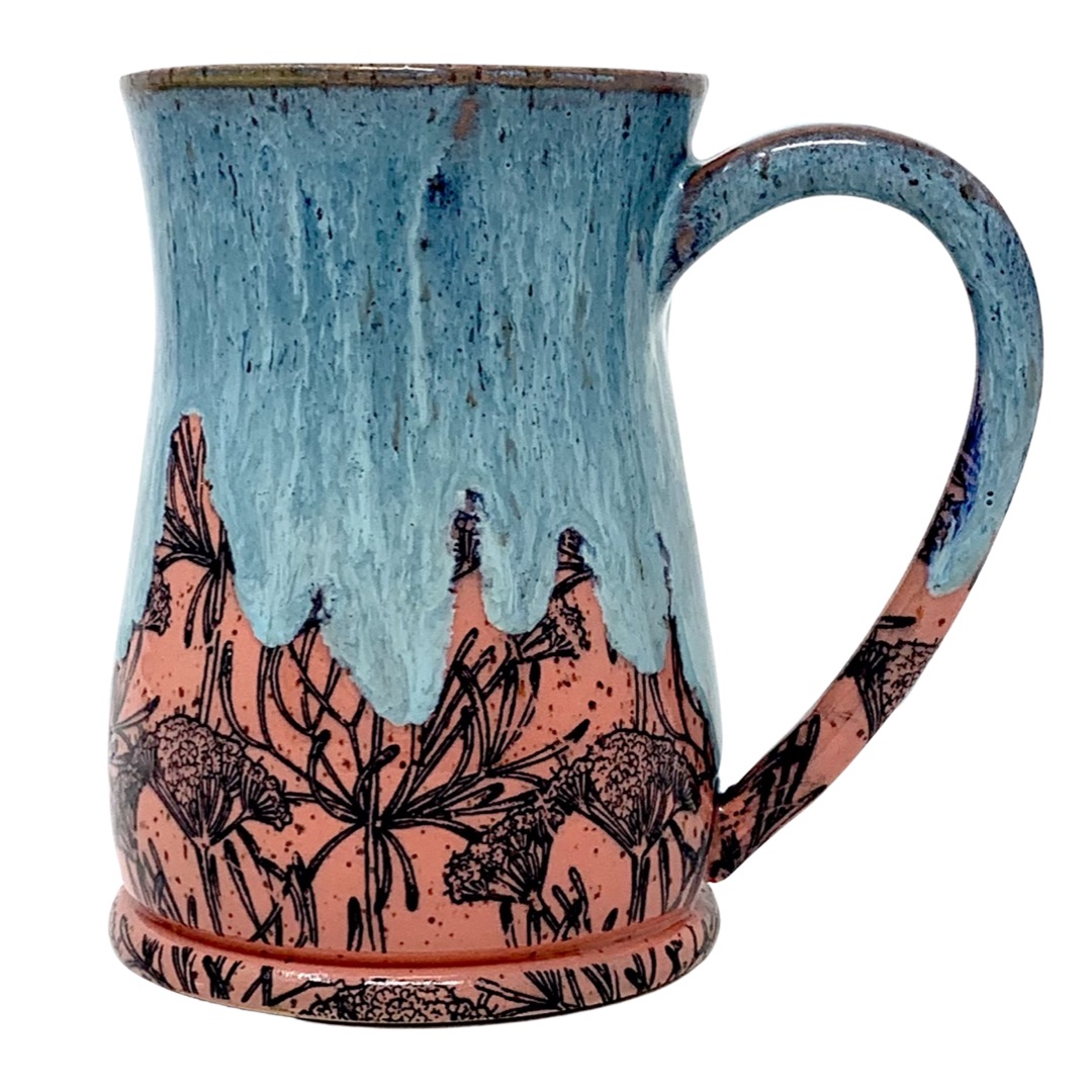 This mug features a distinctive coral-hued base with a detailed botanical design, overlaid by a cool teal glaze that drips from the rim, creating a visual texture that is both organic and striking.