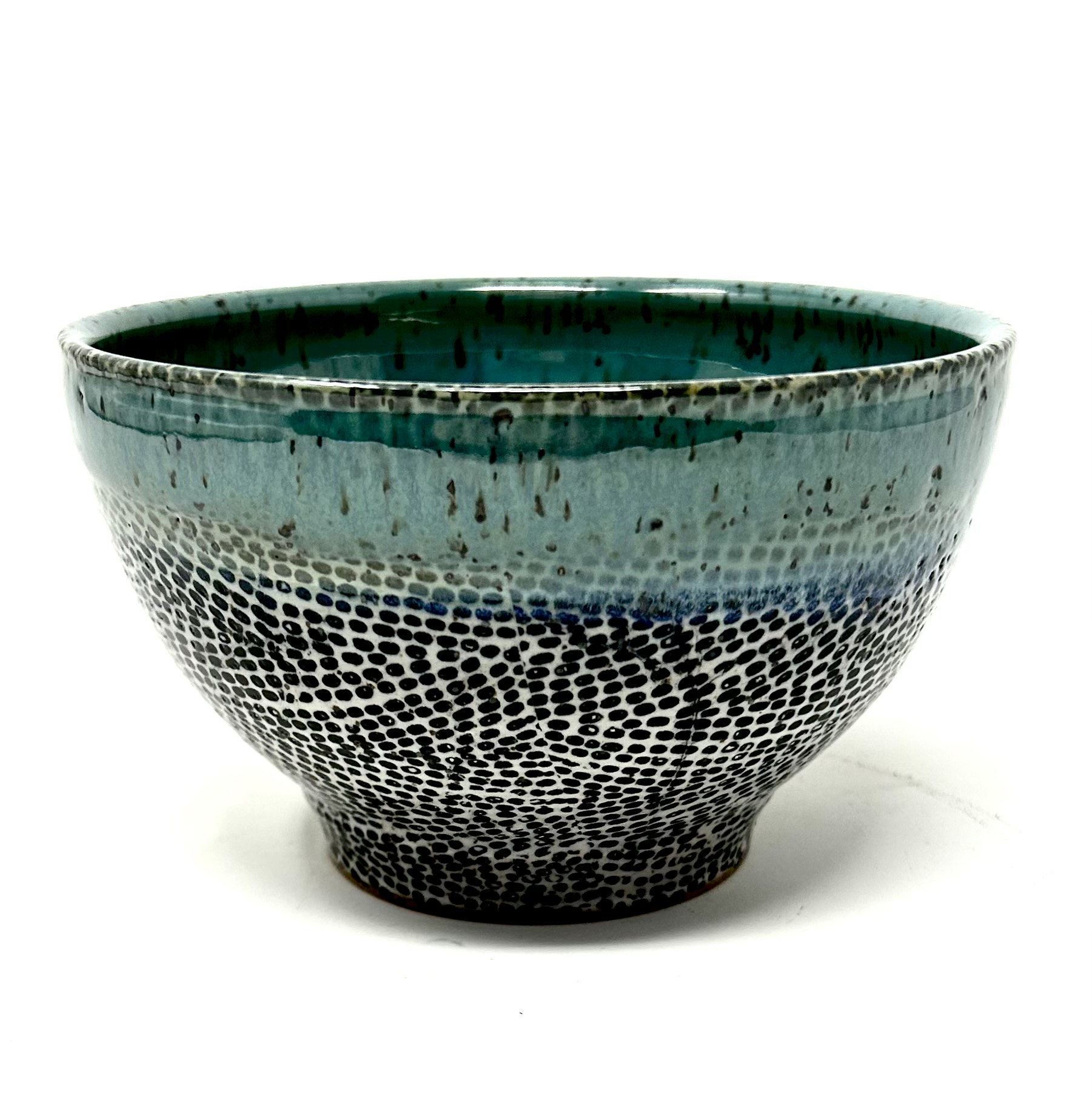 The Zumba Ramen Bowl 2 is a stoneware piece that captivates with a gradient of textures and hues. The speckled pattern at the base, reminiscent of intricate dance steps, rises to meet a serene blue glaze, which then gives way to a lush, green interior.
